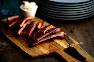 Smoked ribs ready to be eaten on wooden plate.​