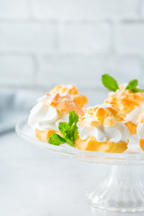 Delicious sweet profiteroles with cream on a modern kitchen table