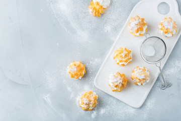 Obraz na płótnie Canvas Delicious sweet profiteroles with cream on a modern kitchen table