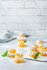 Delicious sweet profiteroles with cream on a modern kitchen table