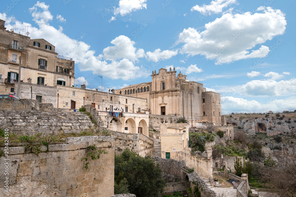 Wall mural The Convent of Saint Agostino sitting on a steep cliff overlooking a deep canyon ravine filled with prehistoric sassi caves in Matera, Italy. An Unesco World Heritage site. Capital culture 2019