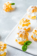 Delicious sweet profiteroles with cream on a modern kitchen table
