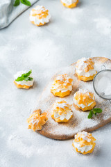 Delicious sweet profiteroles with cream on a modern kitchen table