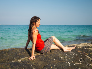 Fototapeta na wymiar Side view of a caucasian woman sitting at a tropical beach.