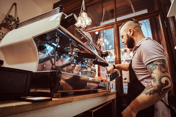 Fototapeta na wymiar Barista wearing apron making a cappuccino, pouring milk in steel mug in a restaurant or coffee shop