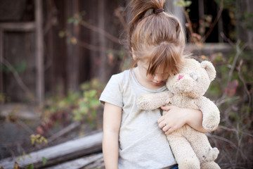 Little Girl Holding Ragged Teddybear Outside - Poverty, Homelessness