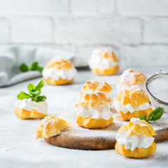 Delicious sweet profiteroles with cream on a modern kitchen table