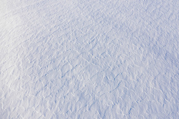 Snow field texture with rough wavy surface. Abstract winter backdrop, high angle aerial view