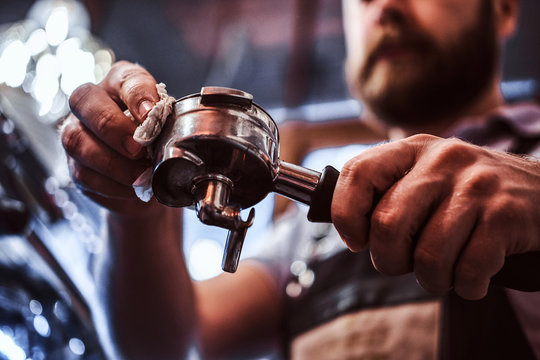 Low angle photo of a barista cleans the portafilter before preparing the cappuccino in a coffee shop or restaurant. Close-up