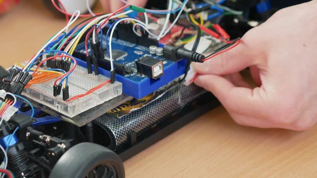 A young engineer assembles a robotic machine. Close up. Classes in robotics for younger students