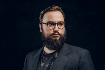 Close-up portrait of a smart bearded man in glasses in a dark studio