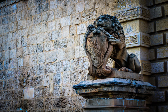 this statue was photographed on the island of Malta in the city of Valletta. The fantastic statue shows the lion sitting. Behind the statue you can see the old wall