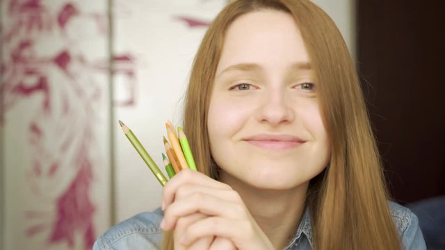 Close-up portrait of a beautiful excited woman drowing with pencils amd smiling 