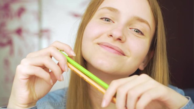Close-up portrait of a beautiful excited woman drowing with pencils amd smiling 