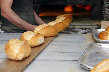 the baker is removing the baked bread from the oven