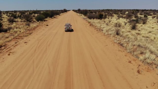 4x4 offroad vehicle driving on sandy dirt trail in southern Botswana Kalahari landscape close to Kgalagadi Transfrontier Park, Aerial drone shot