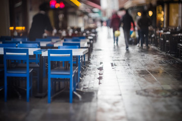 Pedestrians walk between cafes in the rain