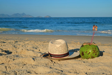 Straw hat with sunglasses and a fresh young coconut on the sandy beach Copacabana in Rio de Janeiro, Brazil, South America