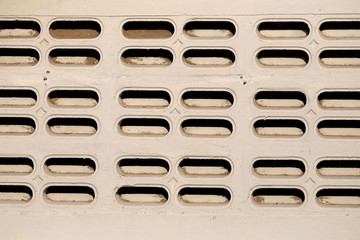 An old wall of a building with brick block vents and sun light 