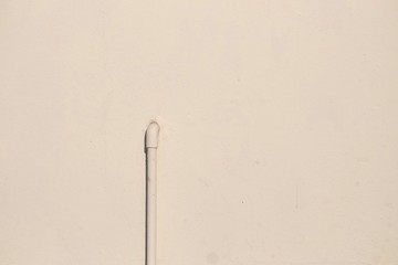 An old water supply pipe on a house wall with sunlight and copy space 