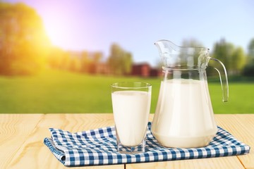 Glass of milk and jug on blurred background
