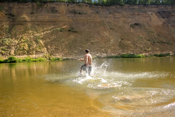 A young man runs, dives into a wide river.  Leisure