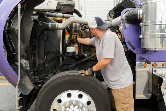 Truck driver checking semi-truck engine
