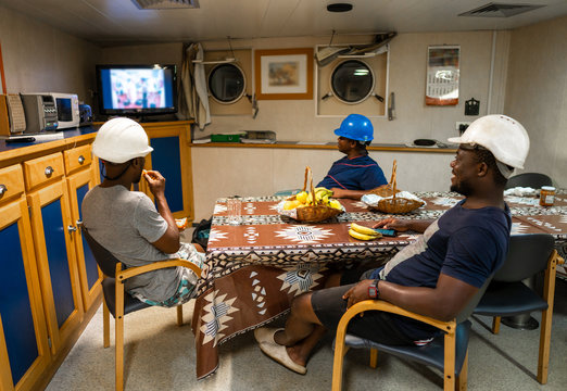 Seamen crew onboard a ship or vessel having fun watching TV. Recreation during at sea