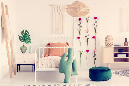 Rattan Chandelier Above Single Metal Bed With Pattered Duvet In Boho Bedroom Interior With Natural Furniture And Flower Board