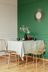 Dining room table with fruits in bowl, flowers in vase and coffee mugs