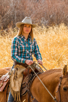 Teenage girl in cowboy hat horseback riding