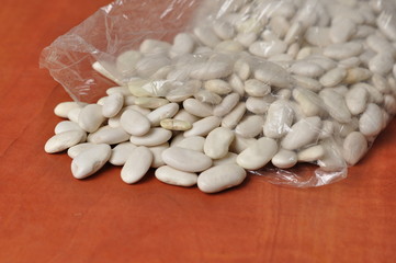 White beans on kitchen orange table. White beans isolated on white background