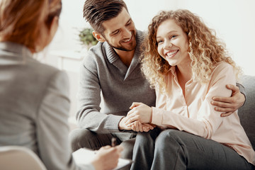 happy smiling husband and wife during therapy session with a psychologist