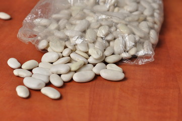 White beans on kitchen orange table. White beans isolated on white background