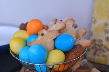 Multi-colored Easter eggs with gingerbread rabbit in metall basket . Yellow, orange and blue.