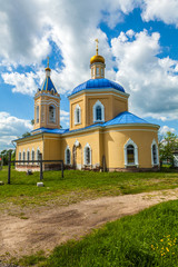 Fototapeta na wymiar Stone Orthodox temple of yellow color with a blue roof and golden domes