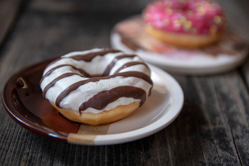 Various donuts on old wooden table. With chocolate fill and nuts, pink glazed and with stars. 