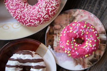 Various donuts on old wooden table. With chocolate fill and nuts, pink glazed and with stars. 