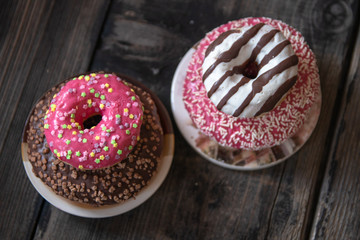 Various donuts on old wooden table. With chocolate fill and nuts, pink glazed and with stars. 