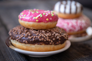 Various donuts on old wooden table. With chocolate fill and nuts, pink glazed and with stars. 