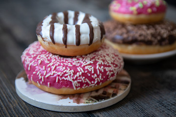 Various donuts on old wooden table. With chocolate fill and nuts, pink glazed and with stars. 