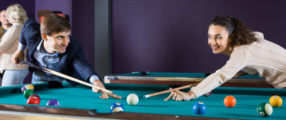 Fototapeta premium smiling young couple playing pool looking at each other