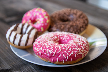 Various donuts on old wooden table. With chocolate fill and nuts, pink glazed and with stars. 