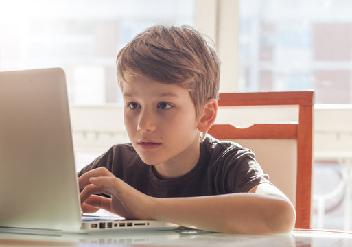 A young boy at home using a laptop to do his homework