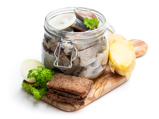 Homemade marinated herring in glass jar with rye bread and jacket potato isolated in white