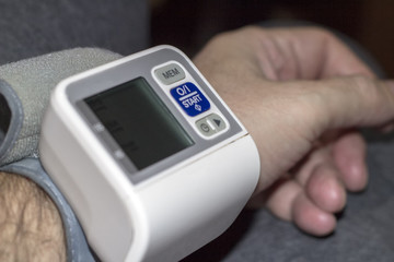 Man check blood pressure monitor and heart rate monitor with digital pressure gauge.Close-up Of man Measuring Blood Pressure At Desk