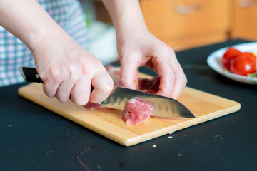 womans hands cut meat on a wooden board b