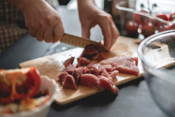 womans hands cut meat on a wooden board b