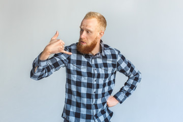Naklejka premium Freestyle. Mature man standing isolated on grey showing call gesture confused