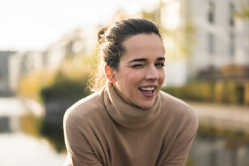 Portrait of winking woman wearing light brown turtleneck pullover in autumn